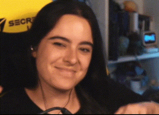 a woman wearing headphones is smiling in front of a yellow shirt that says secret