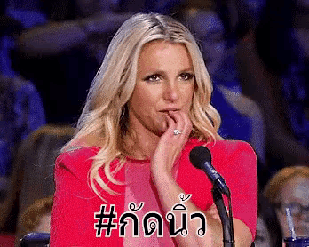 a woman in a red dress is sitting in front of a microphone and making a funny face .