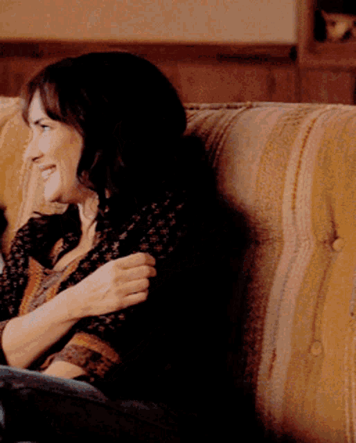 a woman is sitting on a couch with her arm around her chest