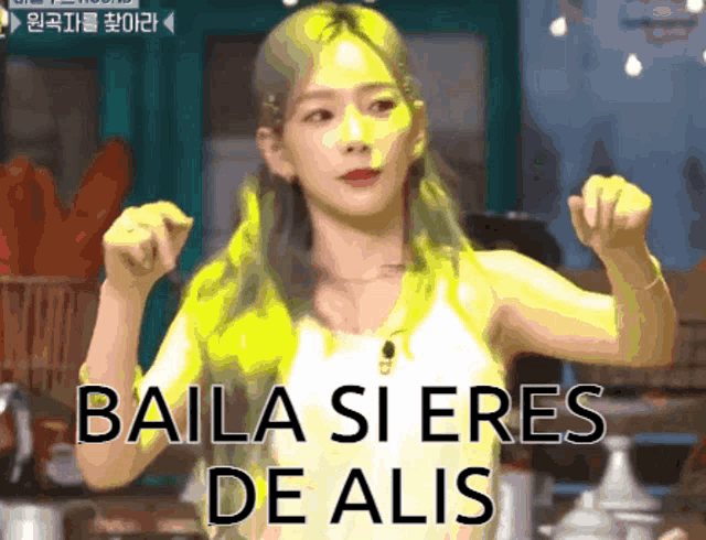 a woman with yellow hair is dancing with the words baila si eres de alis written below her