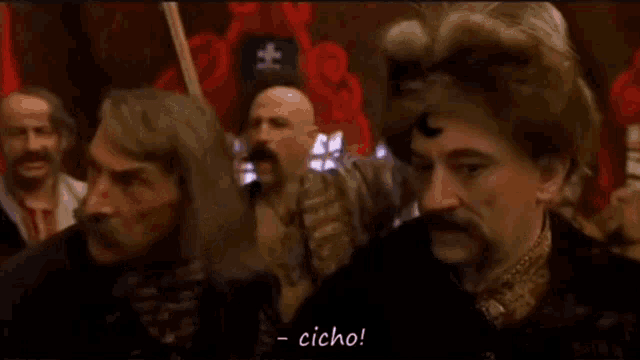 a group of men are standing next to each other in a room and one of them is talking .