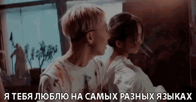 a man is kissing a woman on the cheek in front of a window in a foreign language