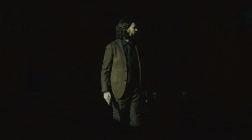 a man in a suit and tie holding two guns in his hands