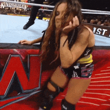a woman in a wrestling ring with a sign that says king queen of the ring