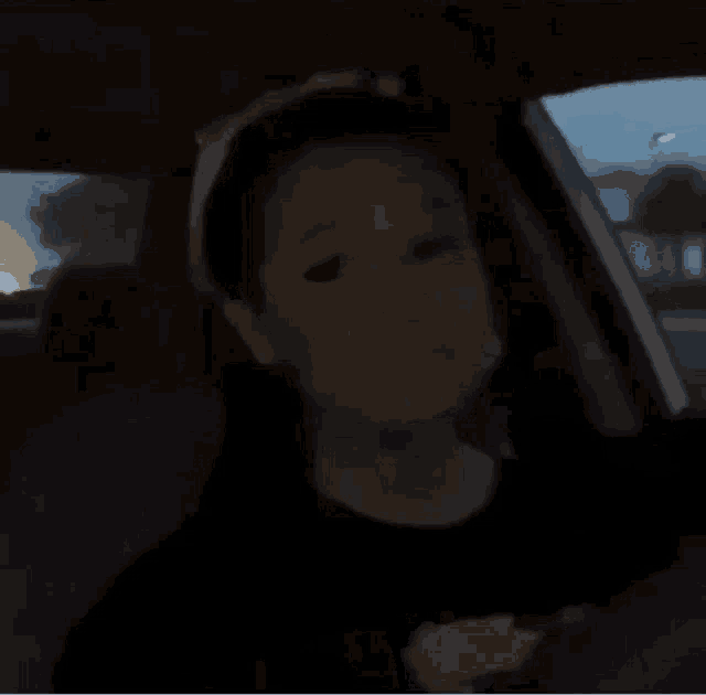 a woman is sitting in the back seat of a car with her hands on her face .