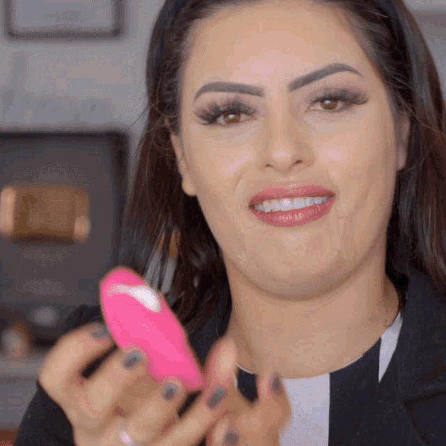 a woman is holding a pink object and smiling