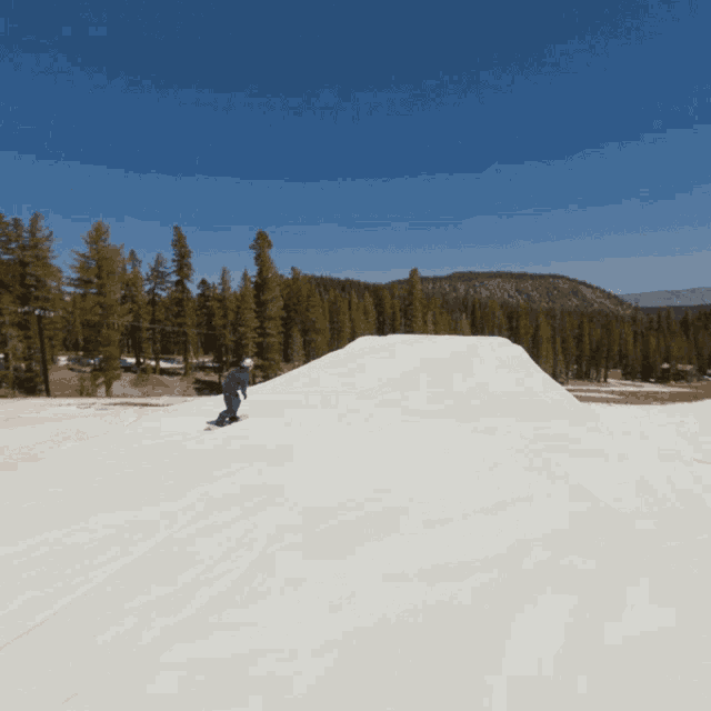 a snowboarder is jumping in the air while riding down a snowy hill