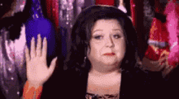 a woman is waving her hand in front of a group of people in a room .