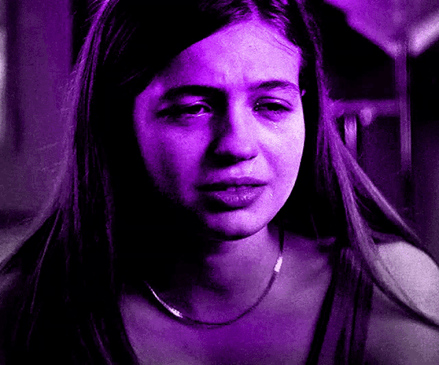 a woman is crying with a purple light behind her