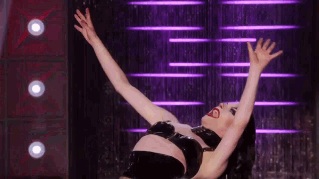 two drag queens are performing on a stage with a red background