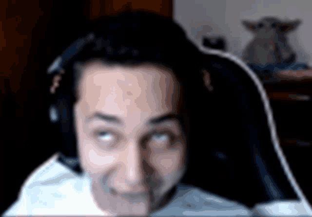 a man wearing headphones is sticking his tongue out while sitting in a chair .