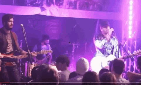 a man singing into a microphone in front of a crowd of people