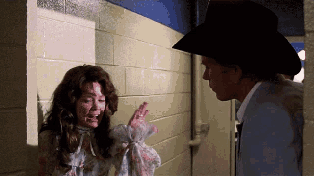 a man in a cowboy hat talks to a woman who is crying
