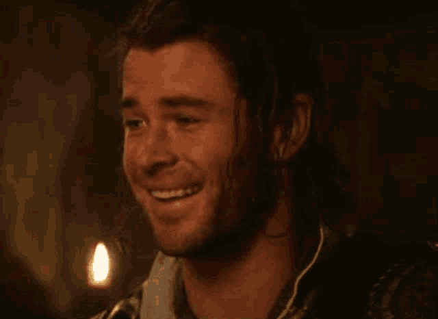 a man with long hair and a ponytail is smiling in a dark room .