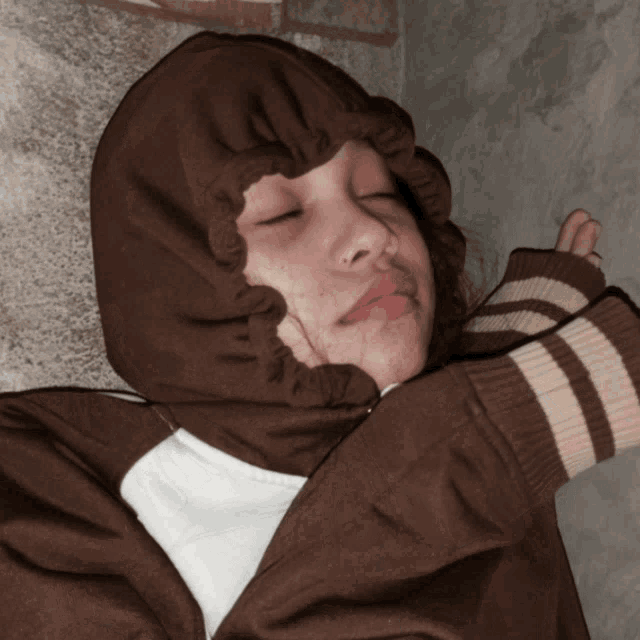 a young boy wearing a brown and white striped sweater with a hood on his head