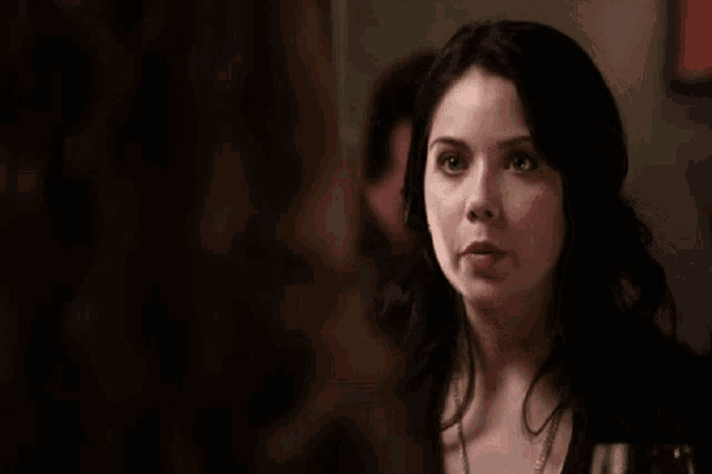 a woman with dark hair is smiling and looking at another woman