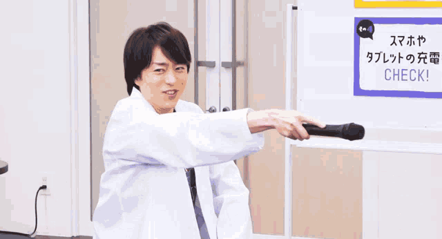 a man in a lab coat holds a microphone and says foooo