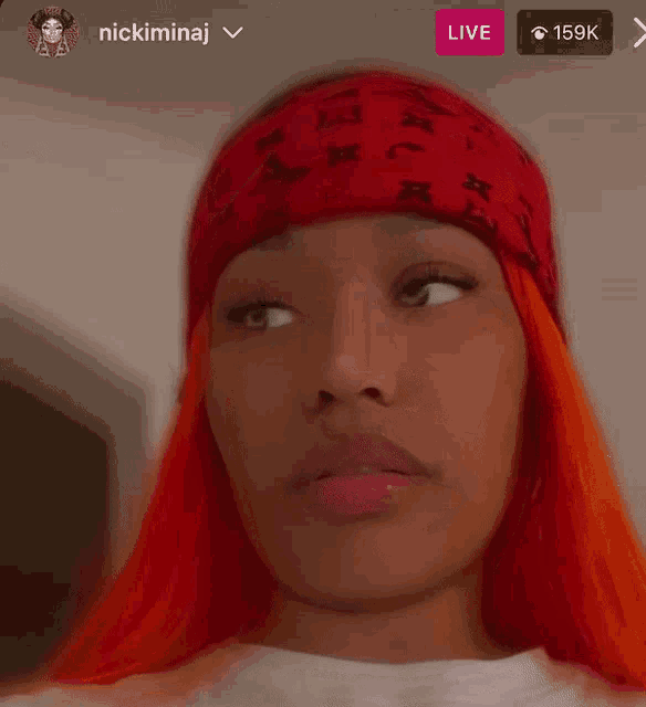 a close up of a woman wearing a red headband with the name nicki minaj on it