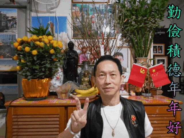 a man giving a peace sign in front of a display of flowers and flags