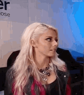 a woman with blonde hair is wearing a red and black plaid shirt and a black jacket .