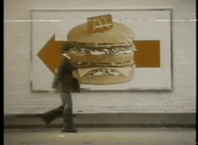 a man walking in front of a mcdonald 's ad