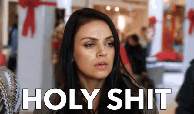 a woman is standing in a shopping mall with the words holy shit written on her face .