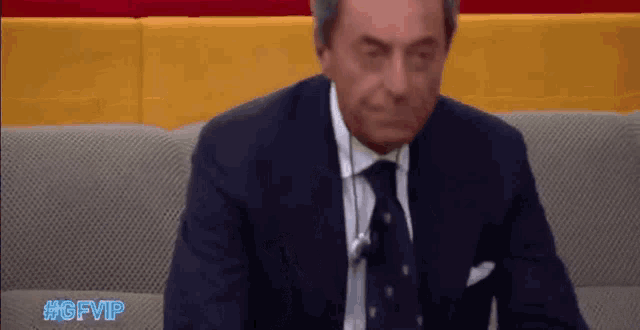 a man in a suit and tie is sitting on a couch with the hashtag #gfvip on the bottom