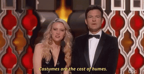 a man and a woman are standing next to each other on a stage and the woman is saying costumes are the cost of humes