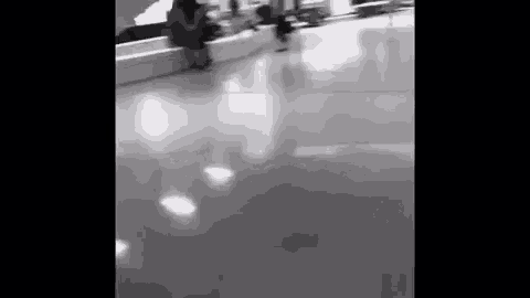 a black and white photo of people walking down a hallway in an airport .