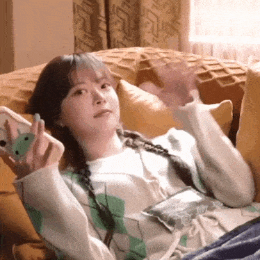 a woman is sitting on a couch holding a cell phone .