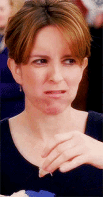 a woman is making a funny face while holding something in her hand