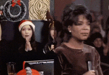 a woman wearing a santa hat sits next to an oprah winfrey