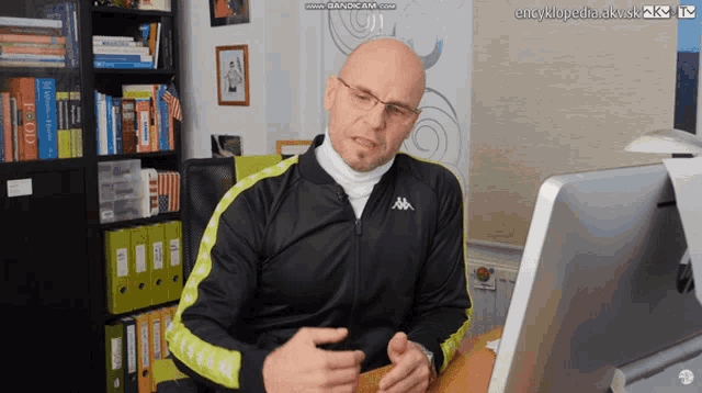a man in a kappa jacket sits in front of a computer screen