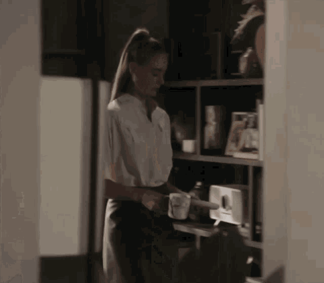a woman in a white shirt is standing in a dark room