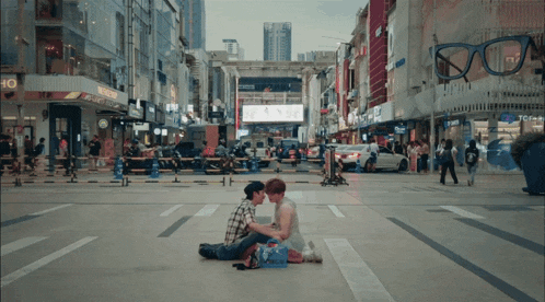 a couple sitting on the sidewalk in front of a store that says tcf on it