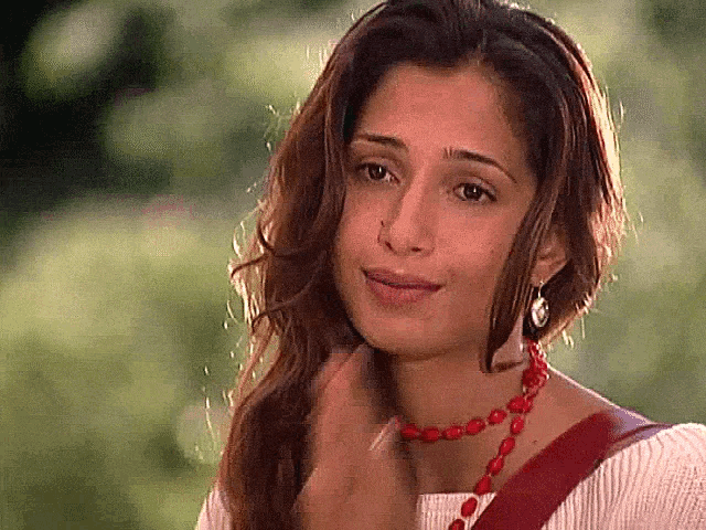 a close up of a woman wearing a red necklace and earrings