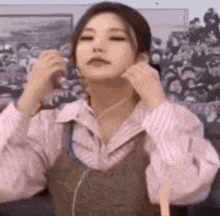 a woman is wearing headphones and adjusting her earring while standing in front of a crowd .