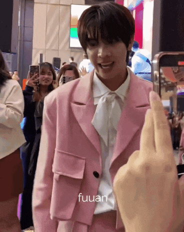 a person is taking a picture of a boy in a pink suit