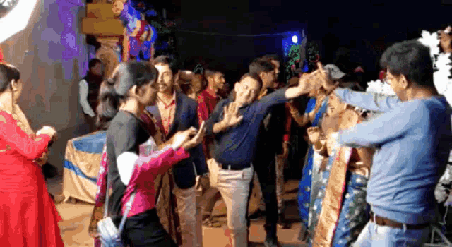 a group of people are dancing in a room and one woman is taking a picture
