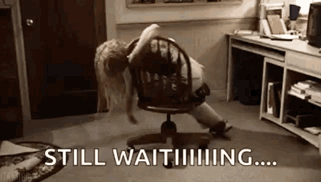 a woman is sitting in an office chair with her legs crossed and the words `` still waiting '' written on the floor .