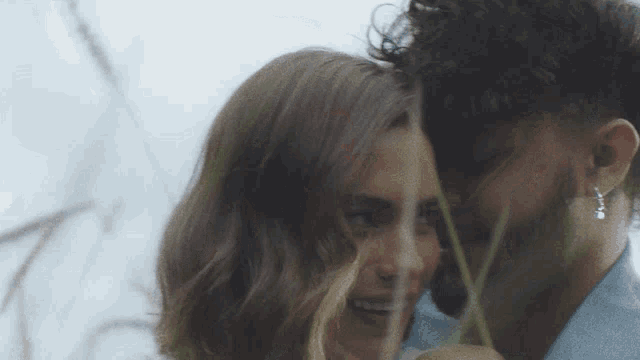 a man and a woman are hugging each other in a field of tall grass