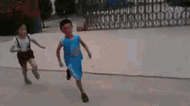 two young boys are running down a street .