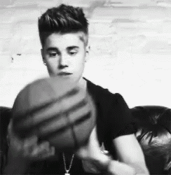 justin bieber is sitting on a couch holding a basketball .