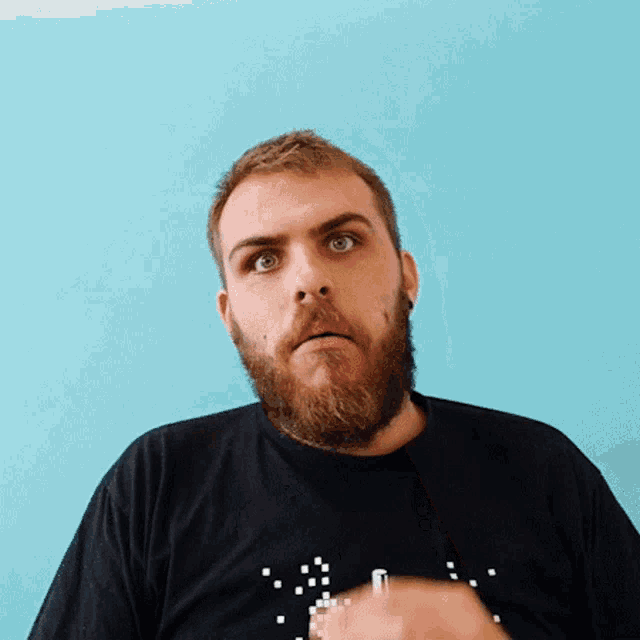 a man with a beard is wearing a black shirt that says ' a ' on the front