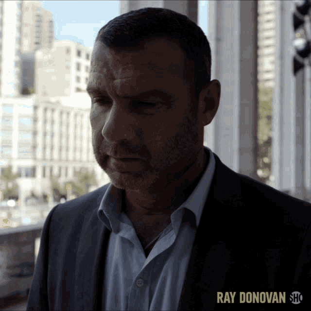 a man in a suit and white shirt with ray donovan show on the bottom right