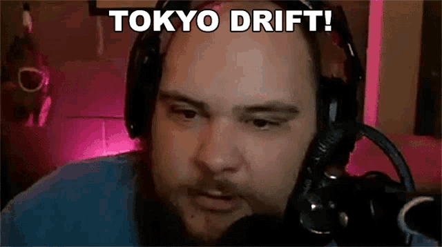 a man wearing headphones and a microphone is talking into a microphone and saying `` tokyo drift '' .