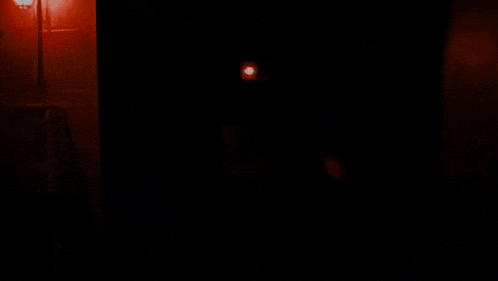 a cartoon character is standing in a dark room with a red light behind it .