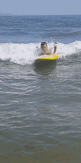 a young boy is riding a wave on a surfboard
