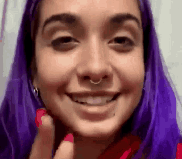 a woman with purple hair and a nose ring smiles
