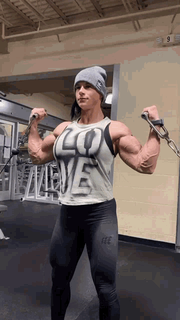 a woman in a tank top that says " love " is lifting weights